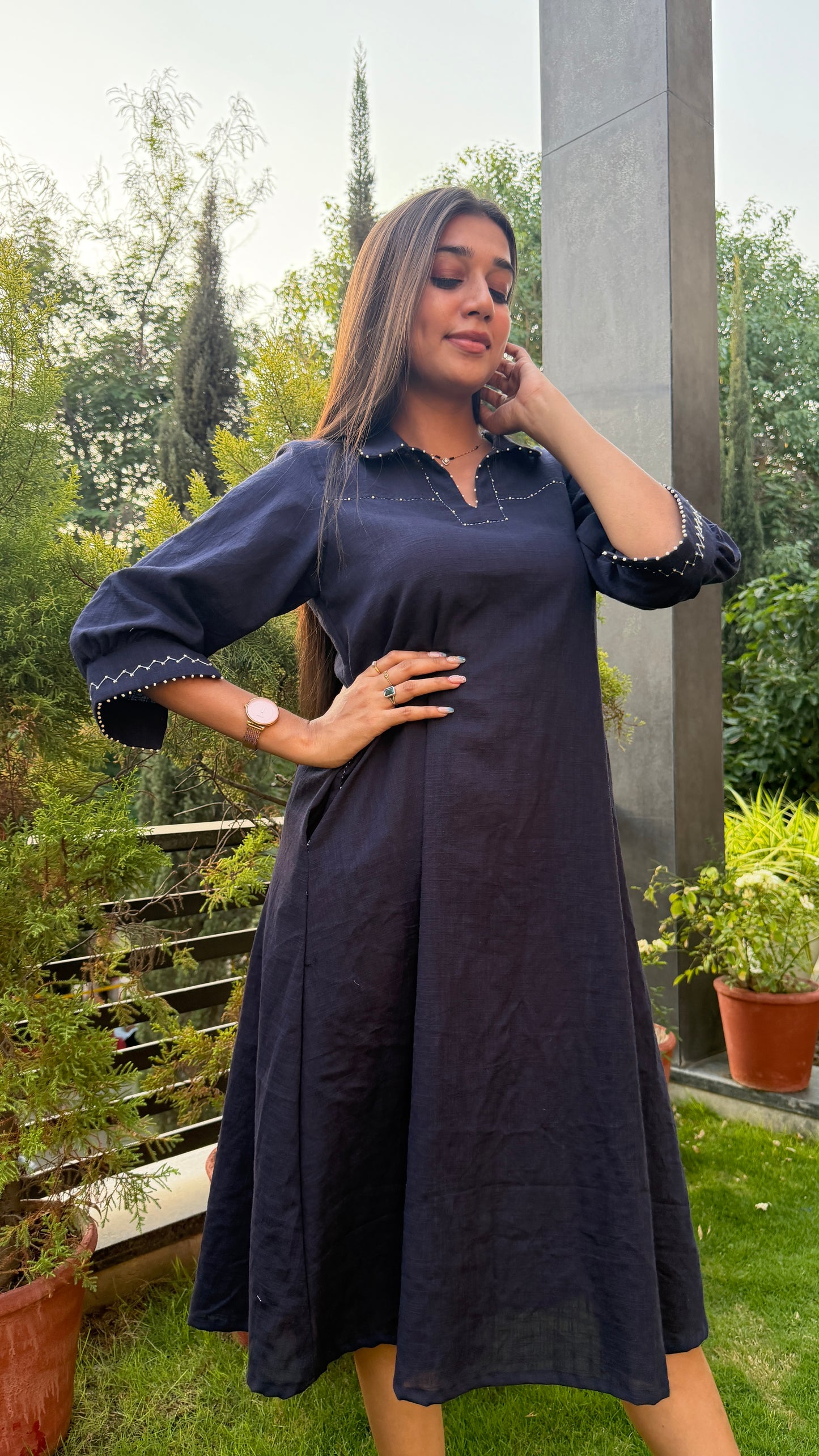 Woman wearing a dark blue dress with a garden background
