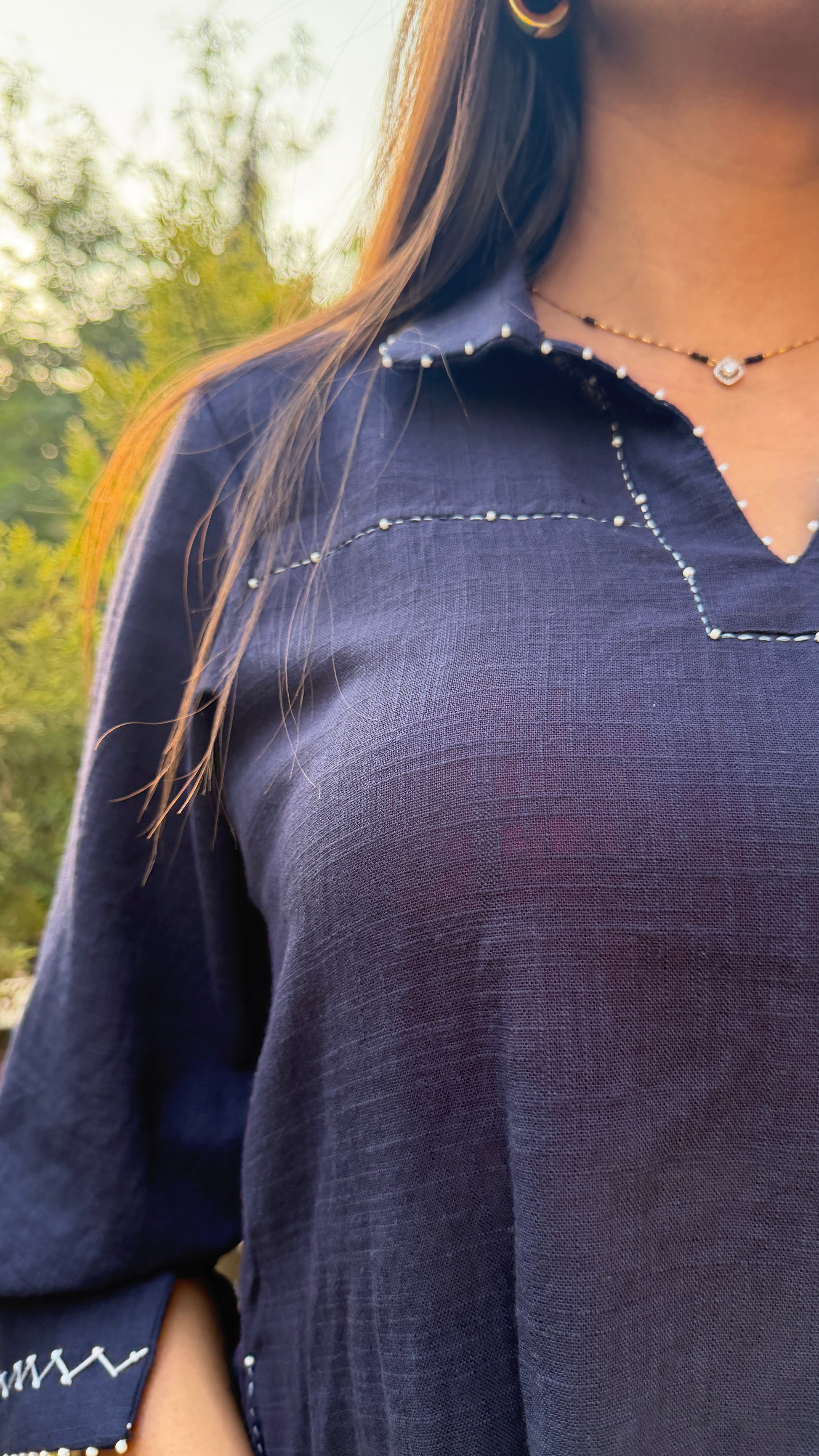 Navy blue top worn by a person with a blurred natural background