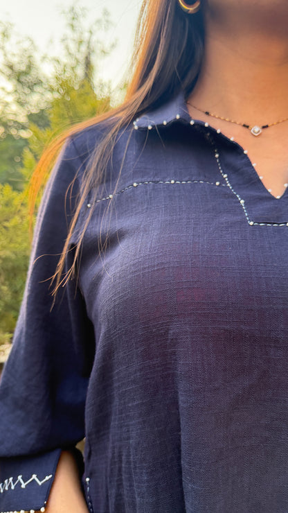 Navy blue top worn by a person with a blurred natural background