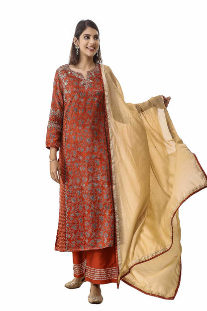 Woman wearing a red and gold traditional outfit with a beige dupatta on a white background