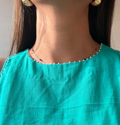Person wearing a Cyan dress with a necklace and earrings.