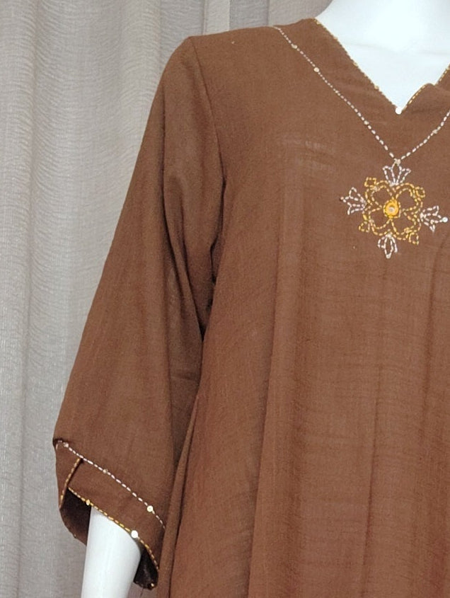 A brown short-sleeved dress displayed on a white mannequin, set against a backdrop of draped gray fabric.